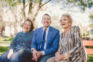 Three people laughing on a park bench