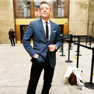 Man in blue suit posing outside grand building